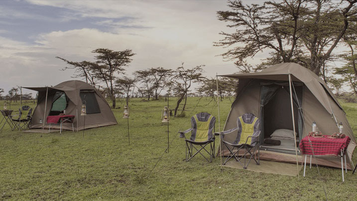Camping tents and chairs in an open grassy setting